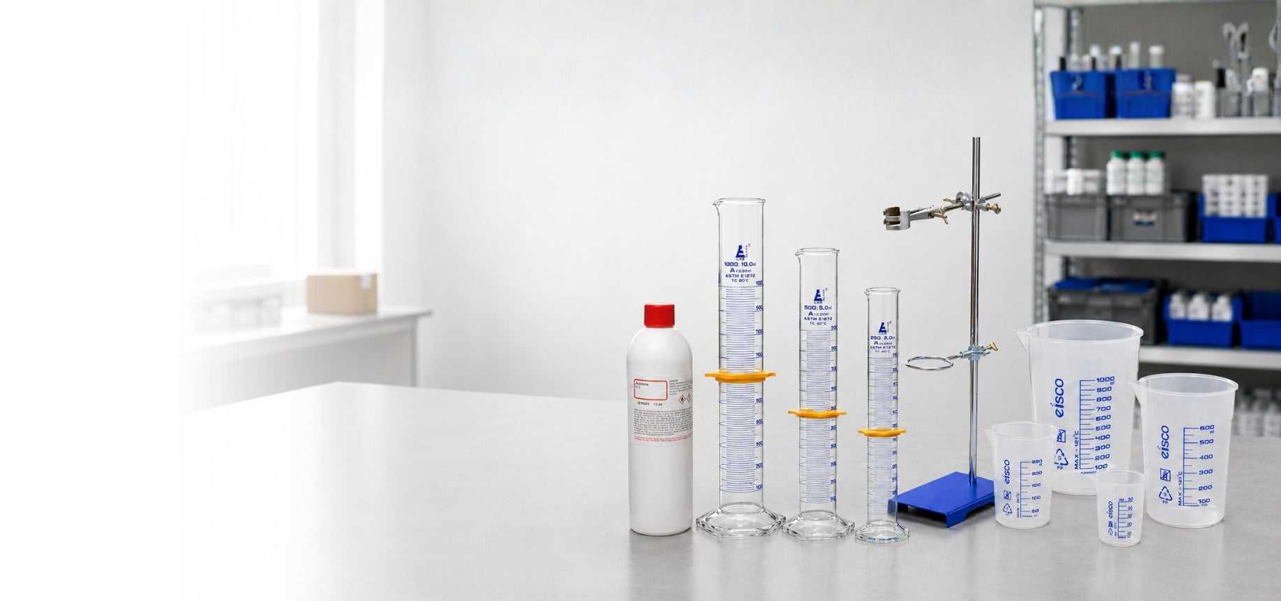 Laboratory setting with measuring cylinders, bottles, and a shelf in the background.